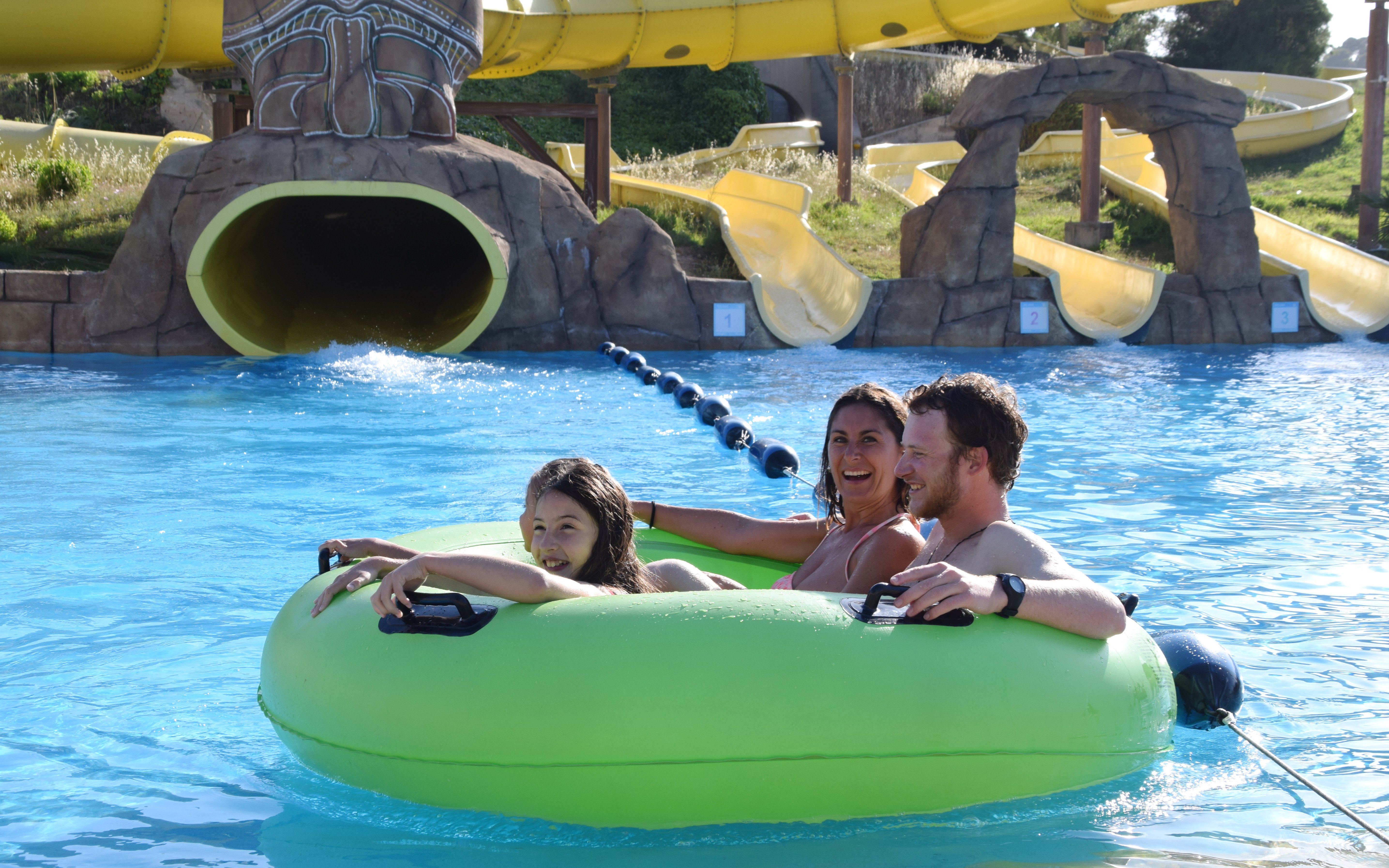 Family enjoying a water slide ride at Aquopolis Costa Daurada, Tarragona.