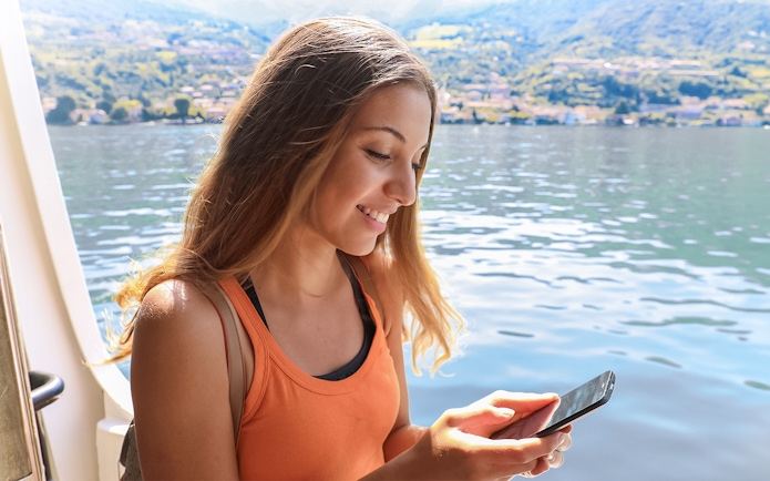 Traveler on ferry enjoying view of Cinque Terre coastline.