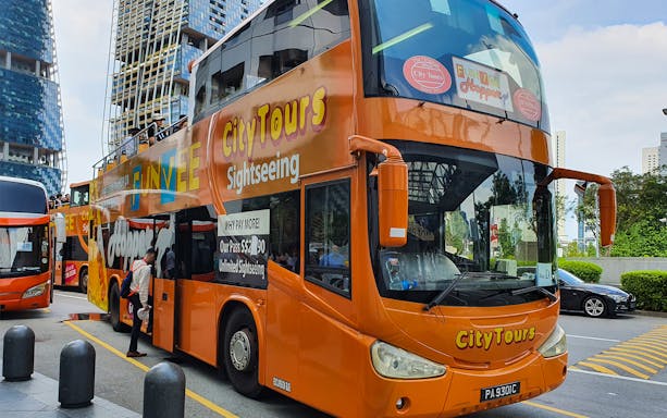 Open-top orange FunVee bus for city sightseeing tour with passengers boarding.
