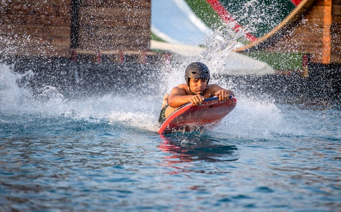 Person bodyboarding at Hatta Wadi Hub water park.