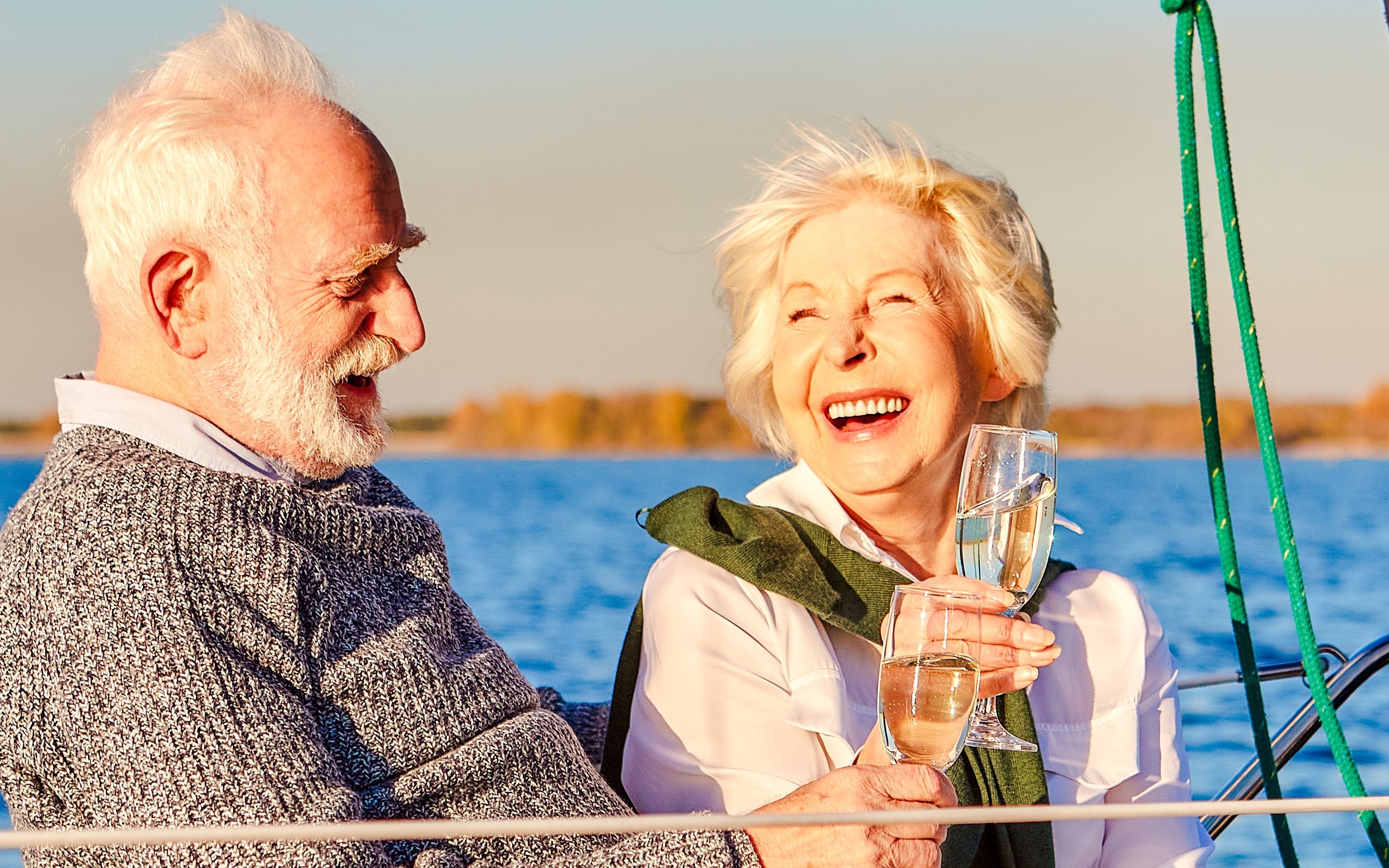 Senior couple enjoying wine on a boat with a scenic lake view.