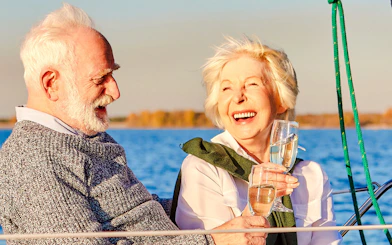 Senior couple enjoying wine on a boat with a scenic lake view.