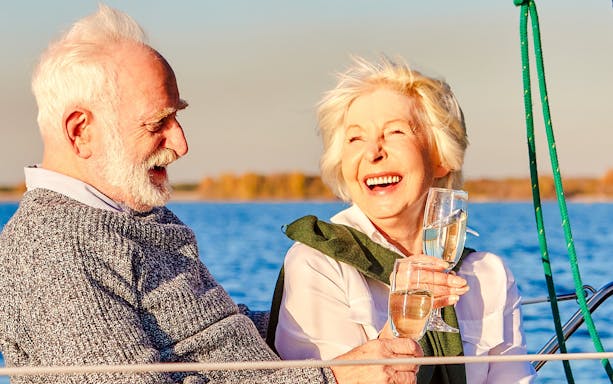 Senior couple enjoying wine on a boat with a scenic lake view.