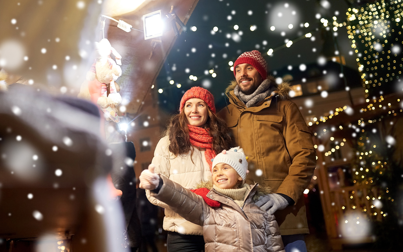 Family enjoying Christmas market with festive lights and snow.