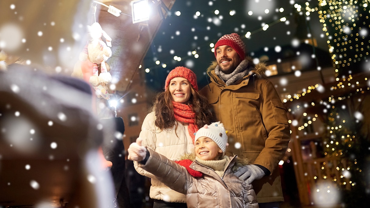 Family enjoying Christmas market with festive lights and snow.