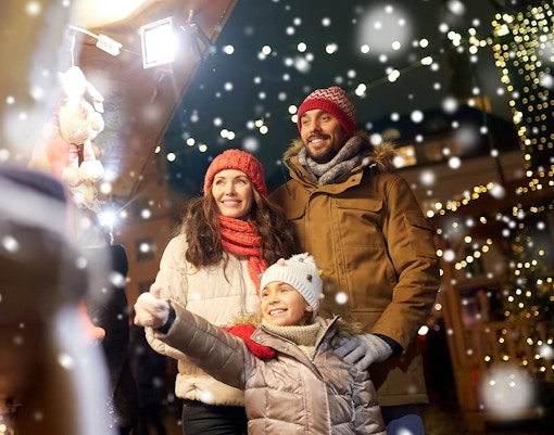 Family enjoying Christmas market with festive lights and snow.