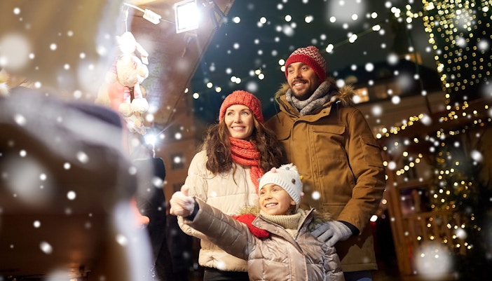Family enjoying Christmas market with festive lights and snow.