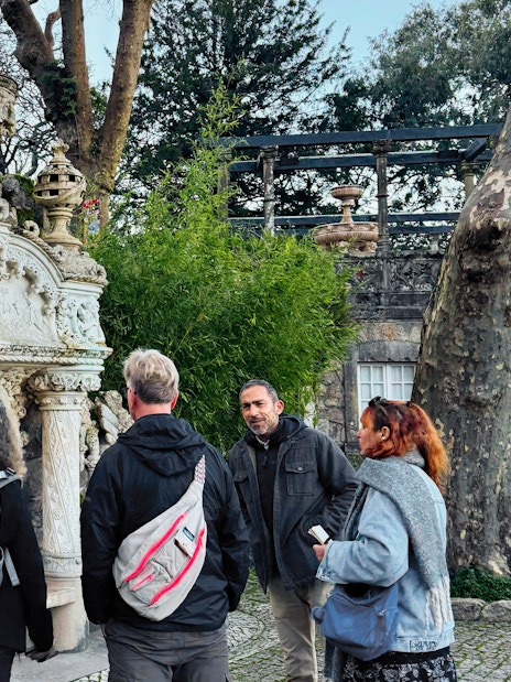 Tourists with guide at ornate stone structure in Quinta da Regaleira, Sintra.