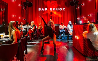 Performer dancing at Bar Rouge Dinnershow with audience seated around tables.