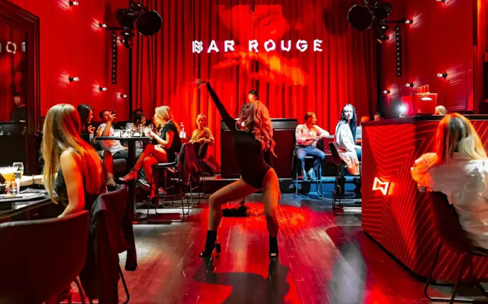 Performer dancing at Bar Rouge Dinnershow with audience seated around tables.