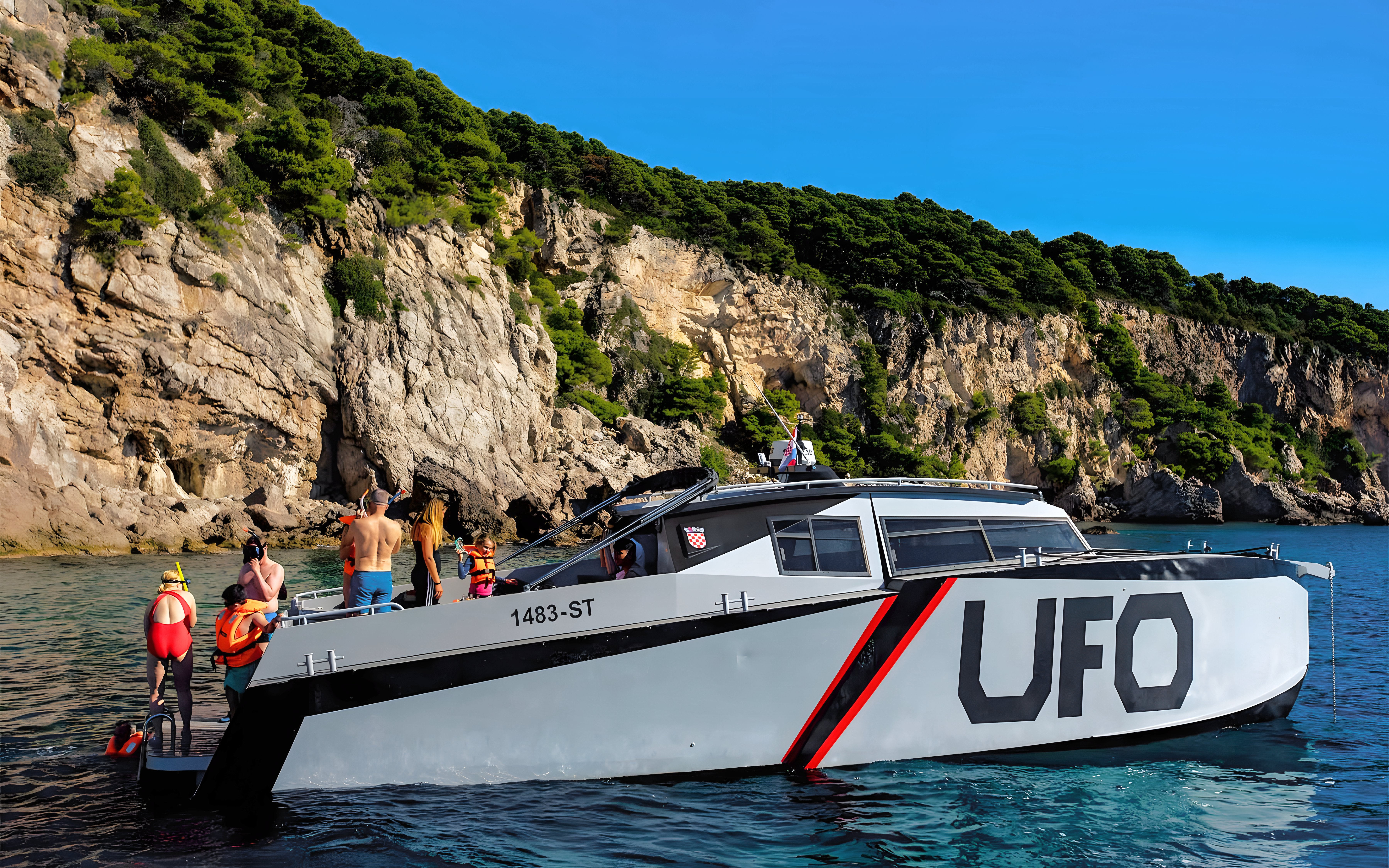 Boat tour with passengers near rocky cliffs in Dubrovnik.