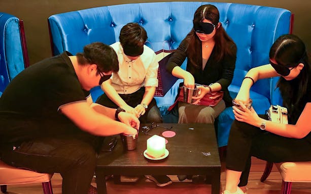 Guests dining blindfolded at a table in Kuala Lumpur's Dining in the Dark experience.