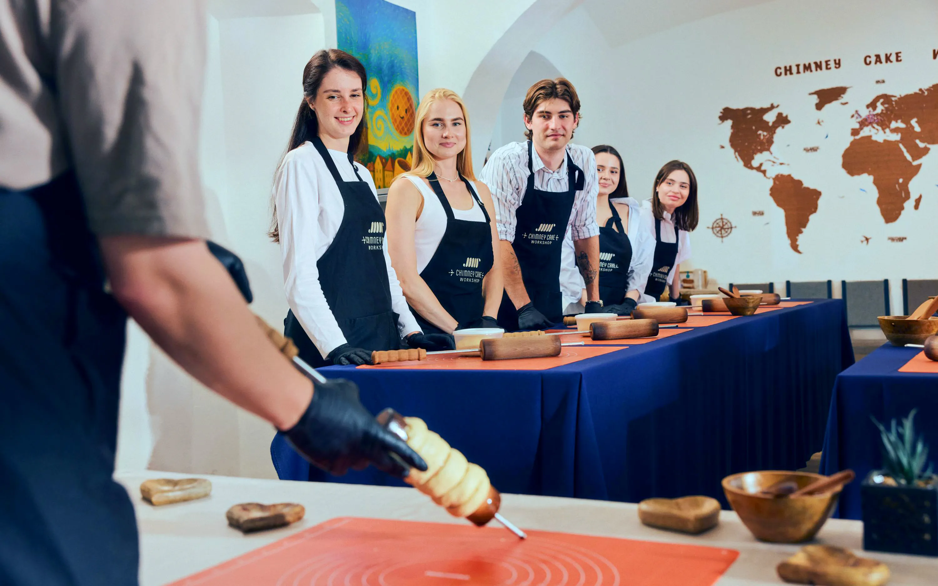 Participants at a Chimney Cake Workshop in Budapest preparing Kürtőskalács.