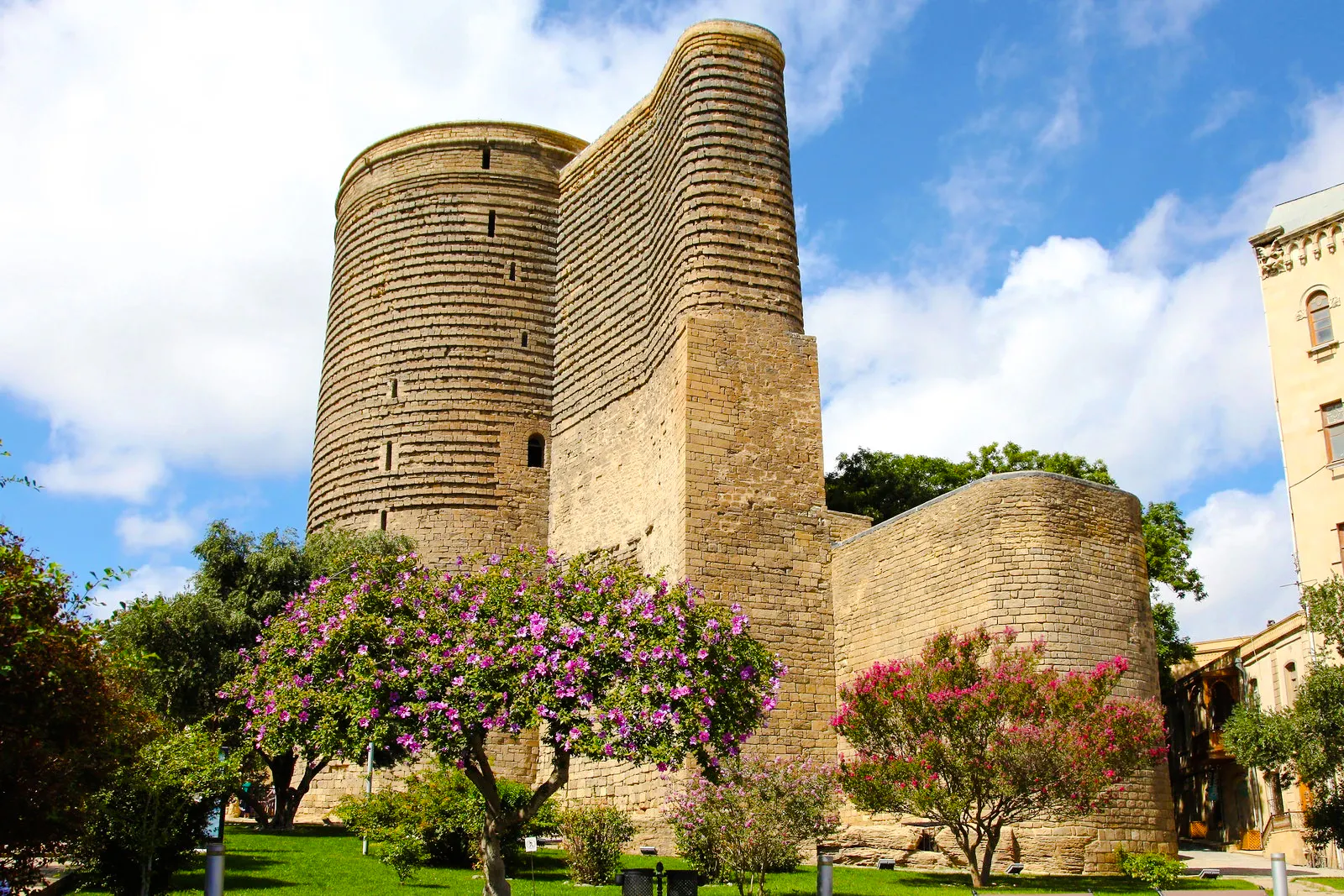 Maiden Tower in Baku surrounded by blooming trees.