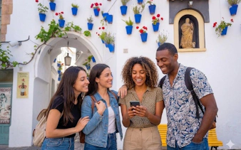 Tourists smiling at a phone in a colorful Andalusian street, Spain.