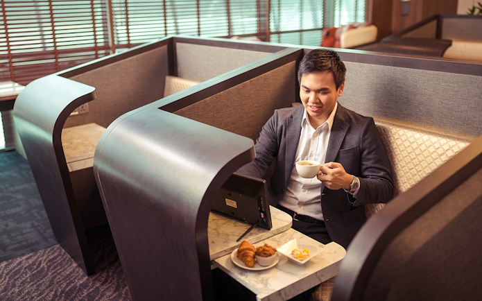 Man enjoying coffee in a private booth at SATS Plaza Premium Lounge, Singapore.