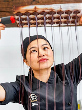 Chocolate maker demonstrating chocolate pouring at Choco Story Brussels.