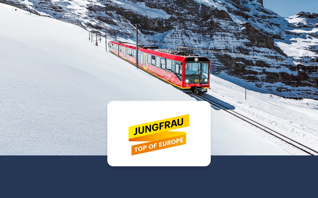 Red train on snowy tracks in Jungfrau region, Switzerland, with mountain backdrop.