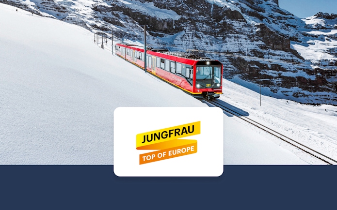 Red train on snowy tracks in Jungfrau region, Switzerland, with mountain backdrop.