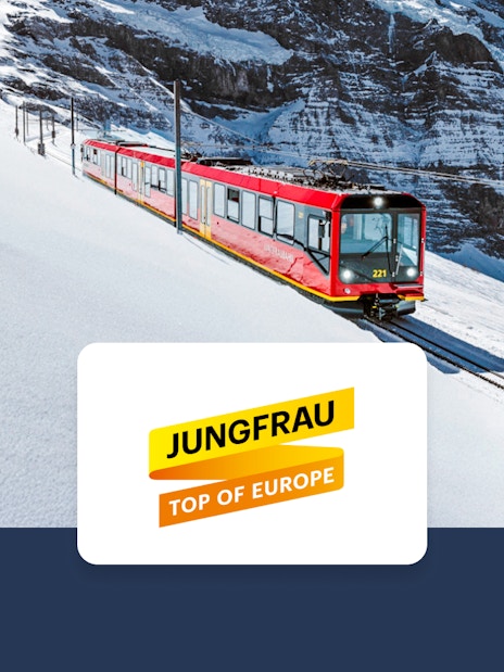 Red train on snowy tracks in Jungfrau region, Switzerland, with mountain backdrop.