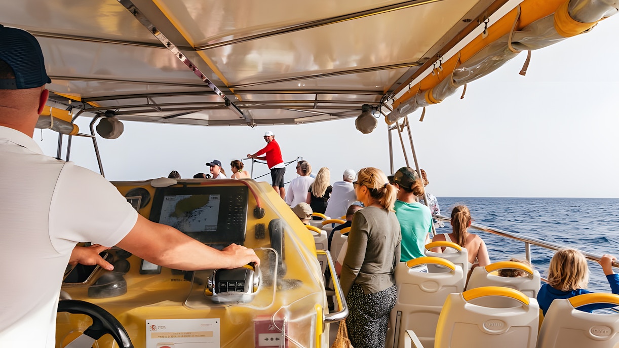 Tourists on a speedboat during a sunset dolphin cruise, with a guide steering the boat.