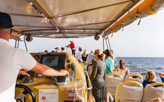 Tourists on a speedboat during a sunset dolphin cruise, with a guide steering the boat.