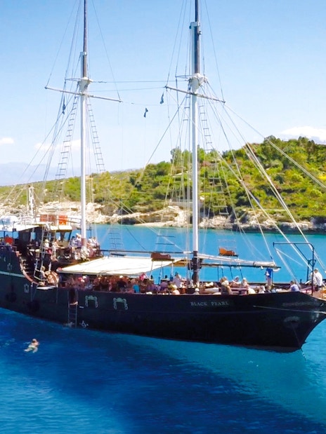 Pirate ship cruising in Souda Bay with swimmers nearby, Crete, Greece.