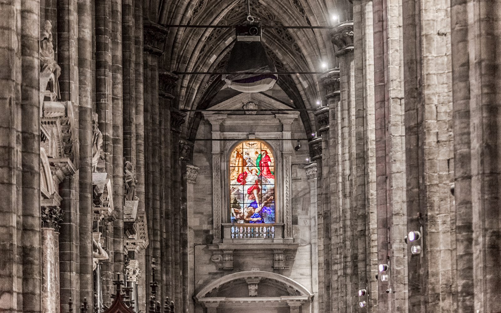 Stained glass window and stone columns inside Duomo Cathedral, Milan.