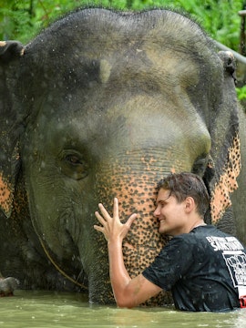 Man hugging elephant in water at Elephant Jungle Sanctuary, Phuket.
