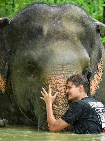 Man hugging elephant in water at Elephant Jungle Sanctuary, Phuket.