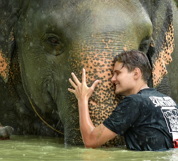 Man hugging elephant in water at Elephant Jungle Sanctuary, Phuket.