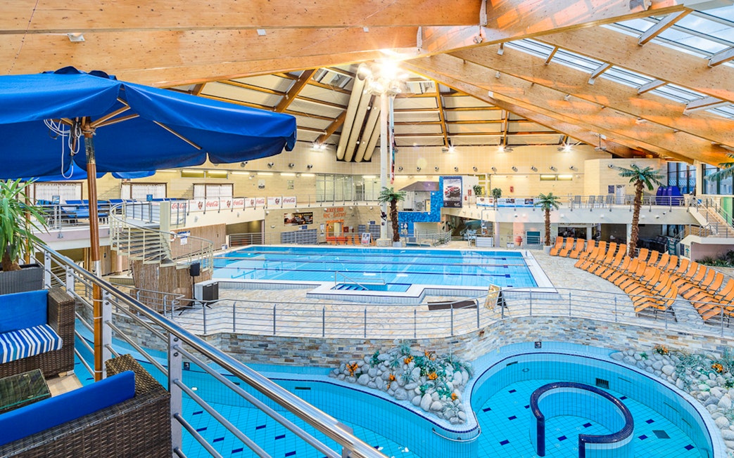 Interior view of pools at Aquapalace Water World with seating and palm trees.