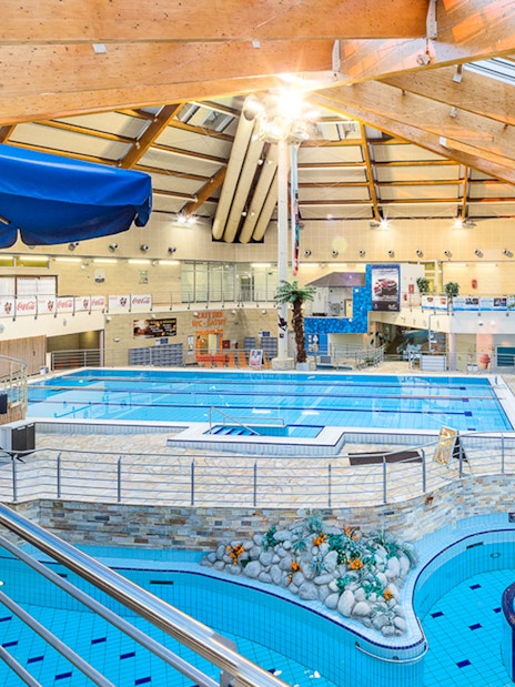 Interior view of pools at Aquapalace Water World with seating and palm trees.