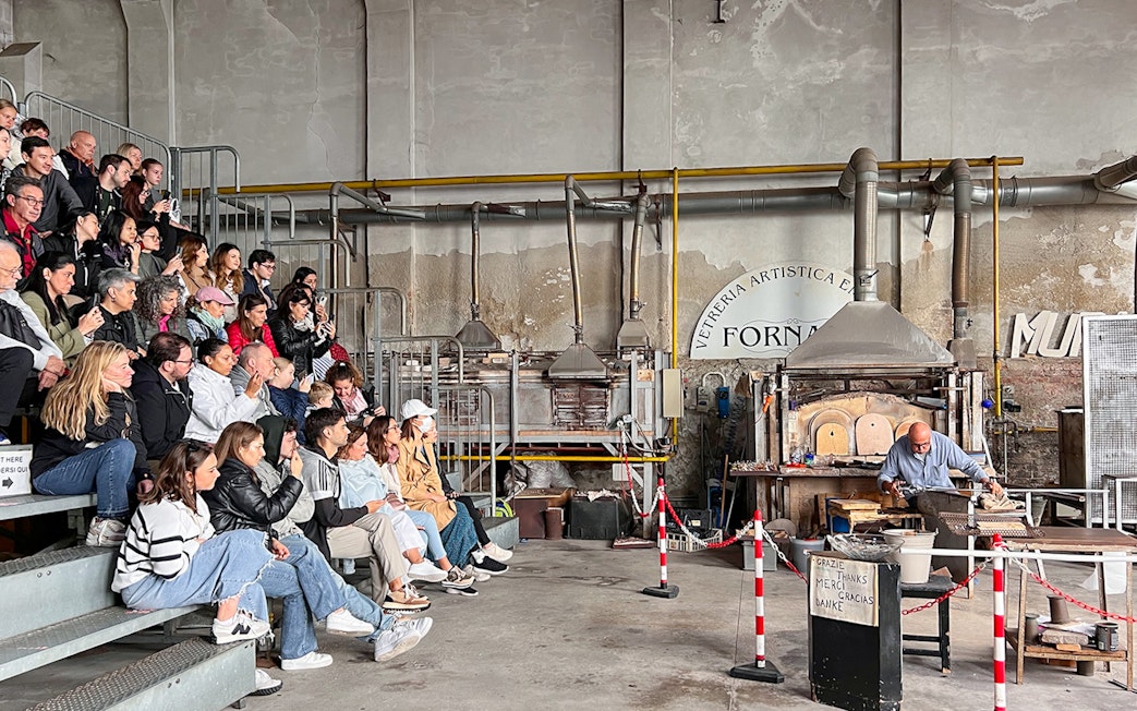 Visitors watching a glassblowing demonstration at a Murano glass factory.