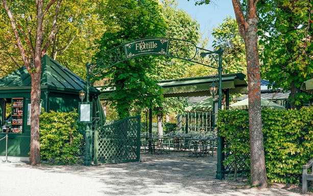 Outdoor dining area at La Flottille restaurant surrounded by trees in Versailles.