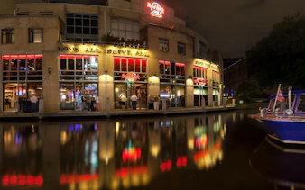 Hard Rock Cafe Amsterdam exterior at night with canal reflections.