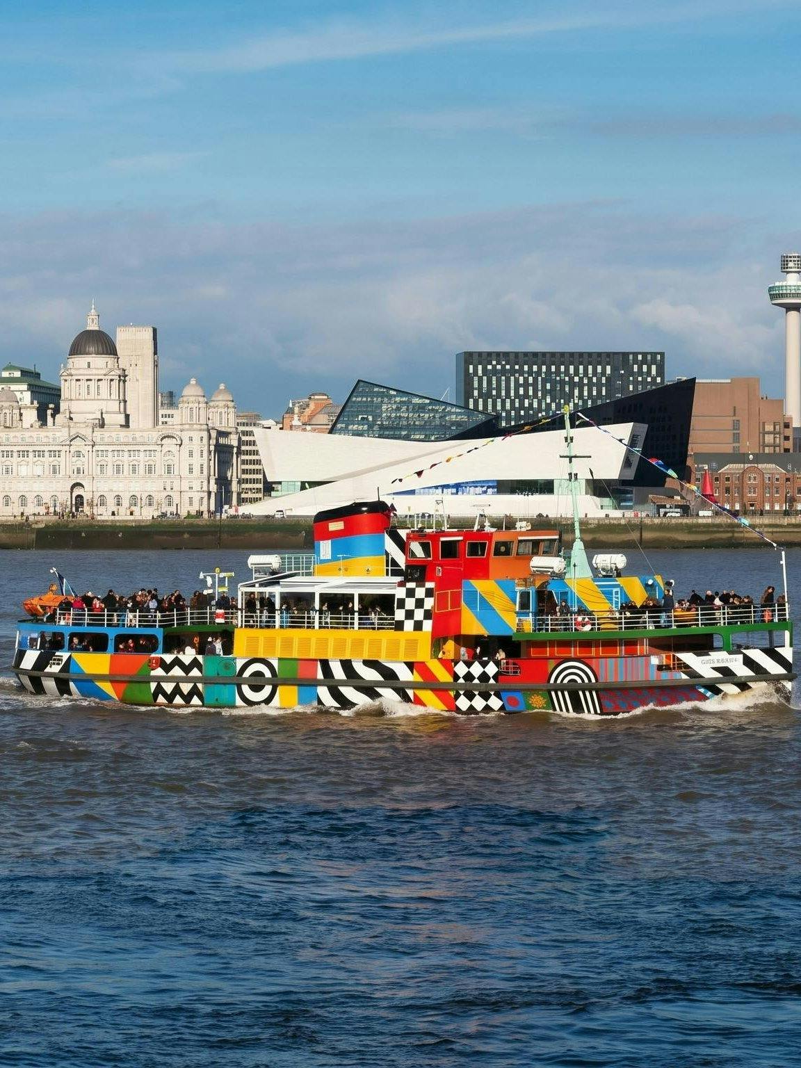 Colorful Mersey Ferry on River Mersey with Liverpool skyline in background.