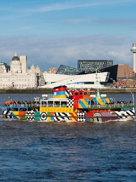 Colorful Mersey Ferry on River Mersey with Liverpool skyline in background.