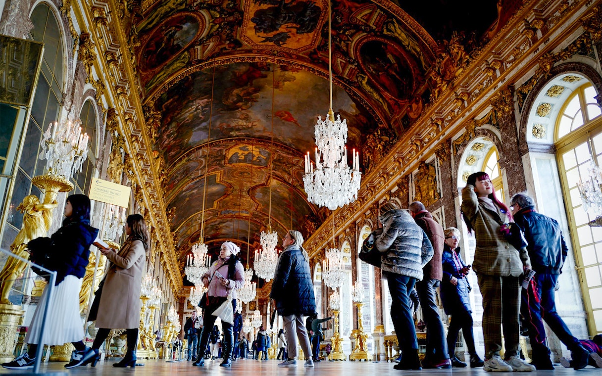 Visitors exploring the ornate Hall of Mirrors in Versailles King's State Apartments.