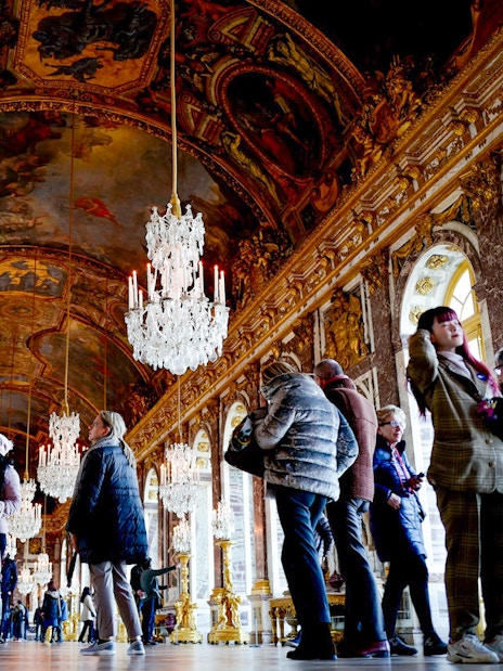 Visitors exploring the ornate Hall of Mirrors in Versailles King's State Apartments.