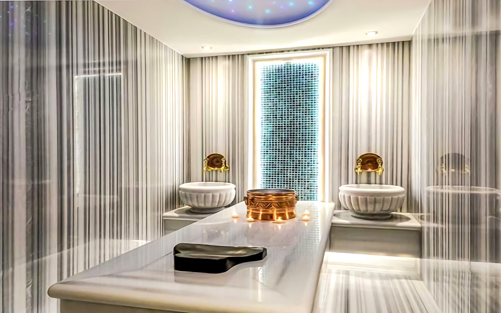 Private Turkish Bath interior with marble table, ornate basins, and ambient lighting.