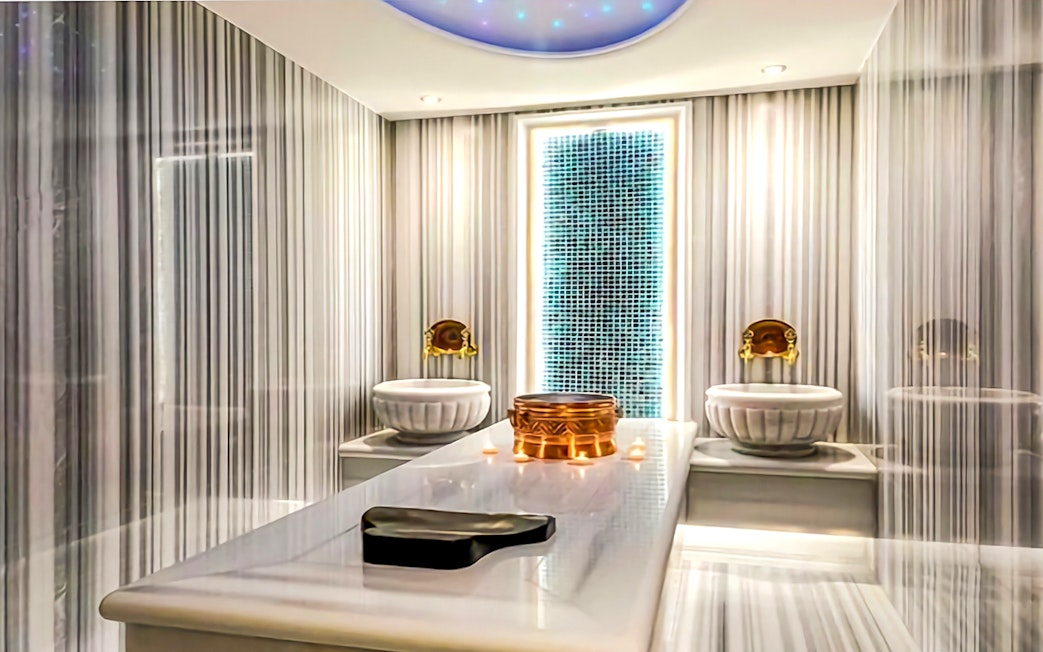 Private Turkish Bath interior with marble table, ornate basins, and ambient lighting.