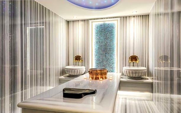 Private Turkish Bath interior with marble table, ornate basins, and ambient lighting.
