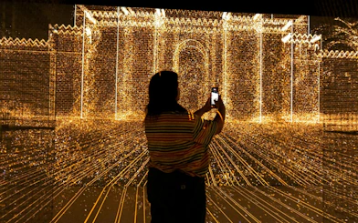 Visitor capturing digital light display at Immerse LDN: Timewalk Exhibition.