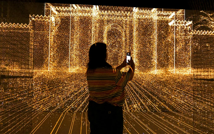 Visitor capturing digital light display at Immerse LDN: Timewalk Exhibition.