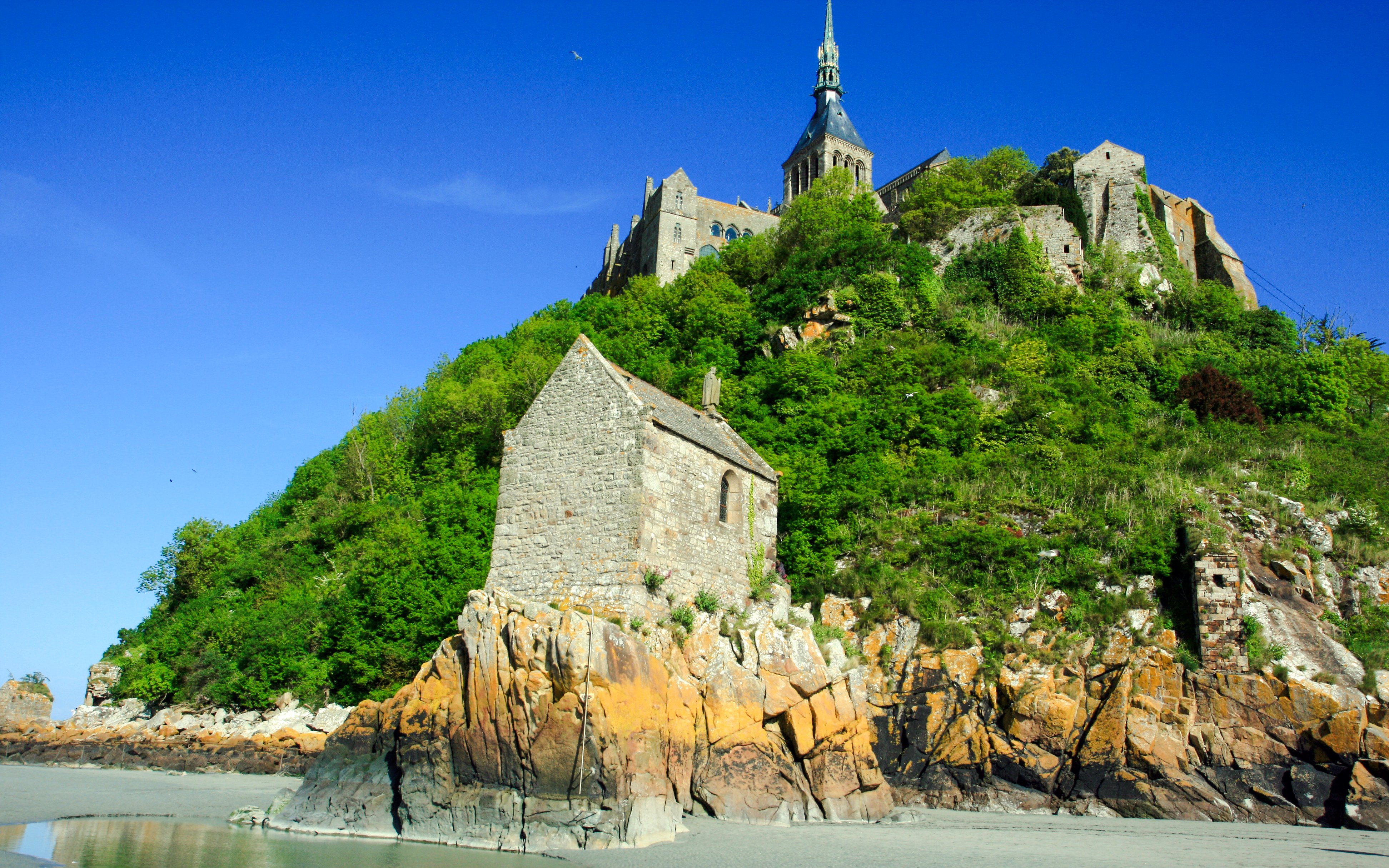 Mont Saint Michel Chapelle du Saint-Aubert on rocky hillside with abbey above.