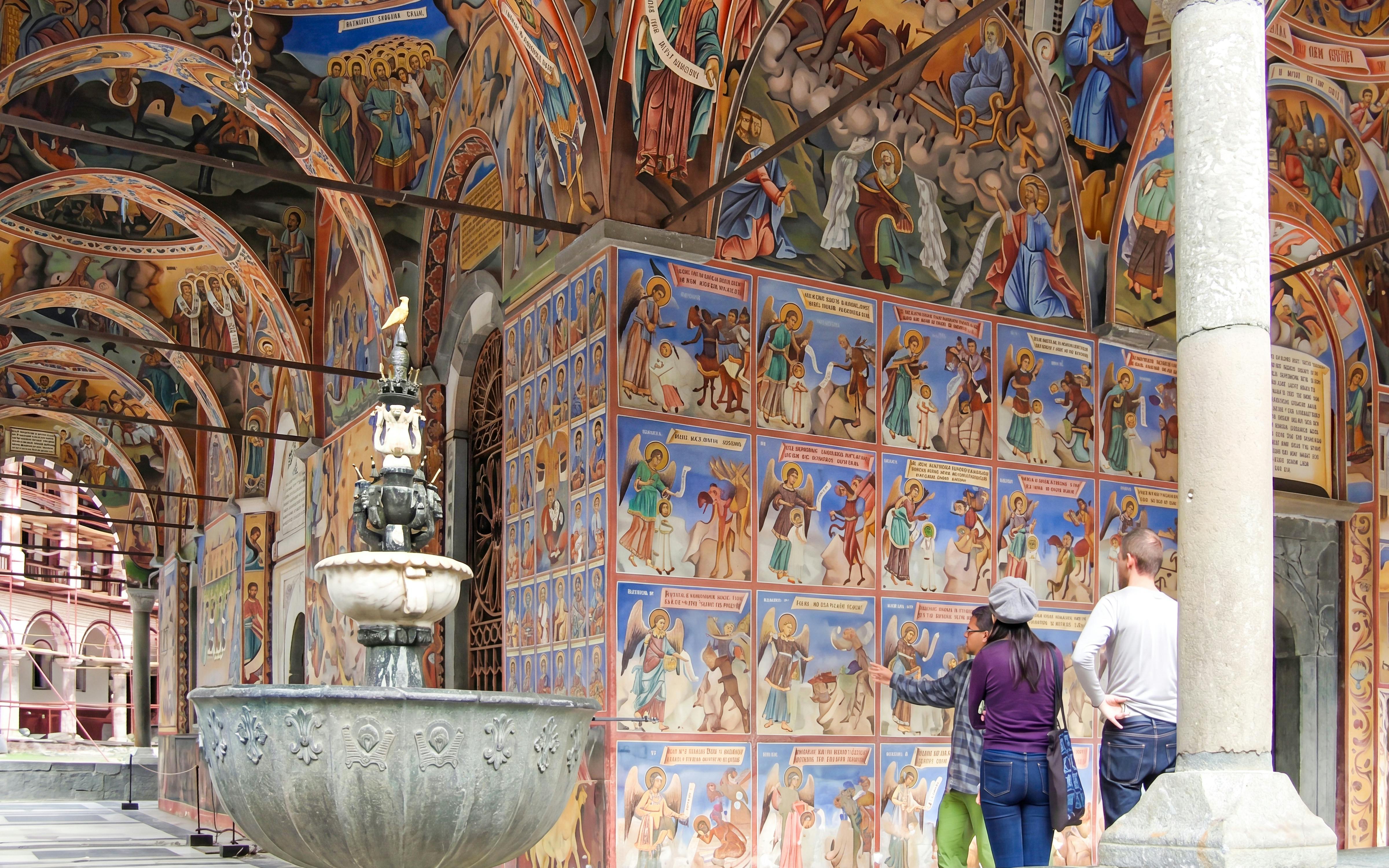 Rila Monastery frescoes with tourists exploring the vibrant religious art, Sofia day trip.