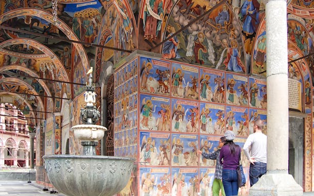 Rila Monastery frescoes with tourists exploring the vibrant religious art, Sofia day trip.