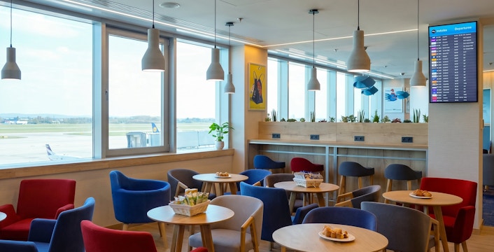 Seating area in Plaza Premium Lounge, Budapest Airport Terminal 2B, with runway view.
