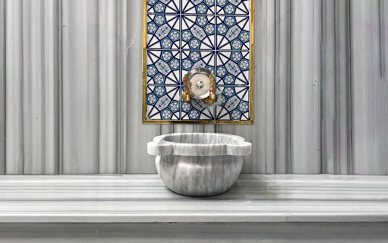 Marble basin and ornate tile wall inside Sifa Hamam.